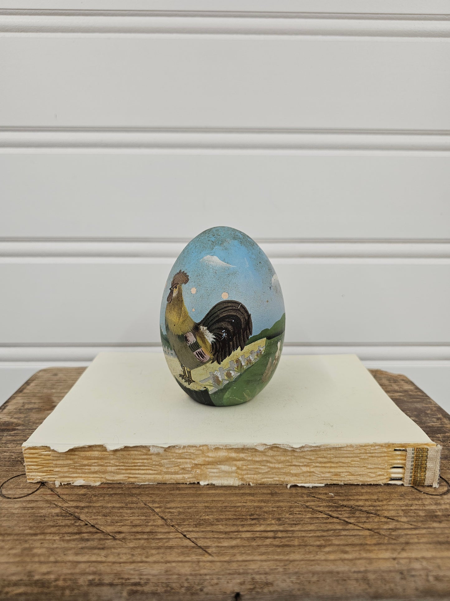 Small round painting of a landscape on a wooden surface with a white wall background