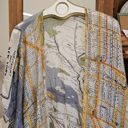 A lightweight open-front cardigan or kimono-style top with an all-over vintage city map print, hanging on a white hanger with a gold ring. The map design features New York City street lines and labels in muted yellow, gray, blue, and black tones.