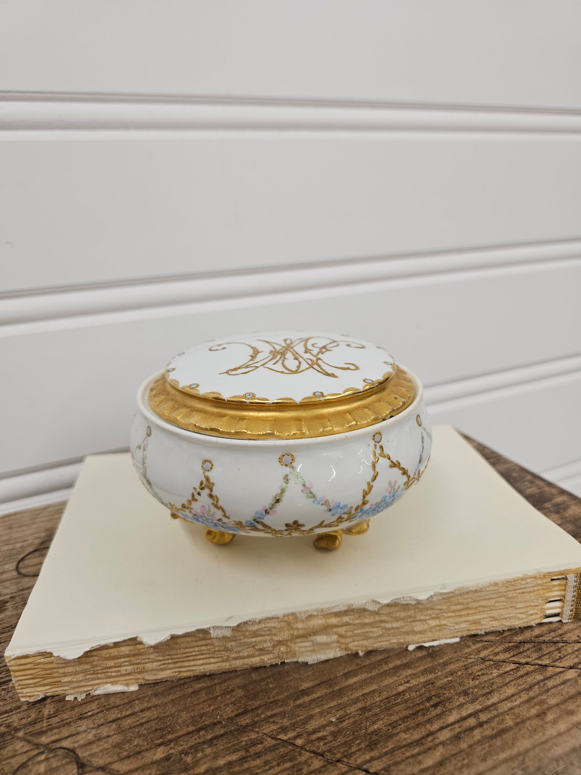 Decorative white and gold clock on a wooden surface with a neutral background