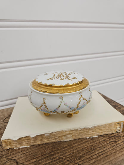 Decorative white and gold clock on a wooden surface with a neutral background