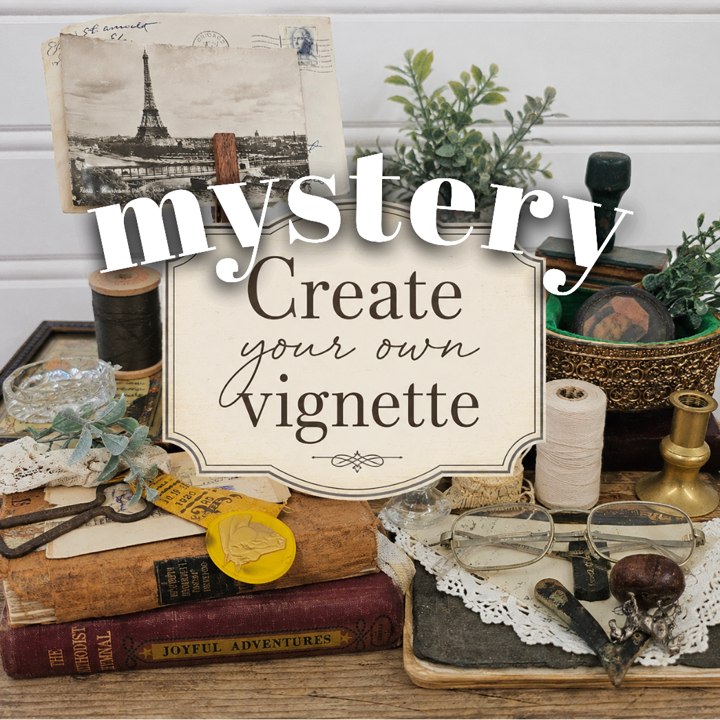 A styled tabletop arrangement with vintage books, scissors, a roll of white tape, small plants, and decorative objects, overlaid with the large text 'mystery Create your own vignette'. This appears to be a promotional graphic or digital listing image rather than a straightforward product photo, so subject_type is best classified as Other.
